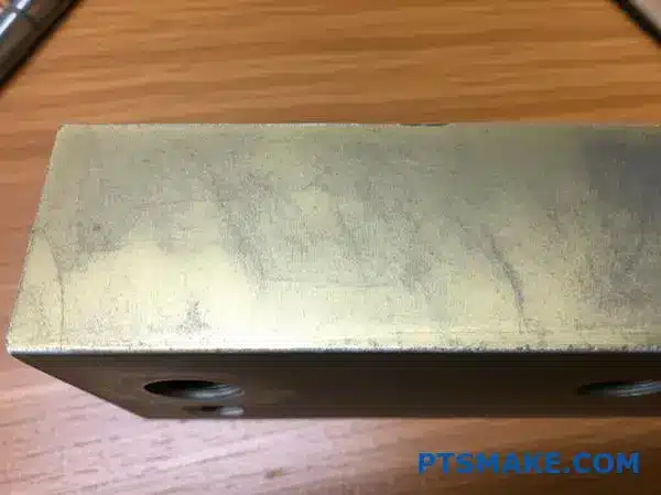 Weathered bronze anodized aluminum component showing surface deterioration and color fading after outdoor exposure