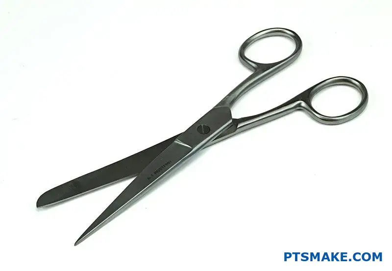 Stainless steel surgical scissors with fingerprint resistant coating on medical examination table surface