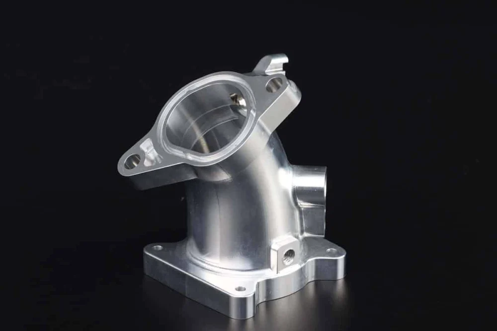 Metal housing with circular ports facing different directions and drilled flange mounting holes