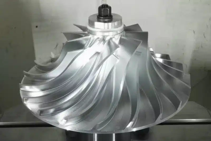 Contoured metal disc with curved blades, a raised center bore and holes around its rim